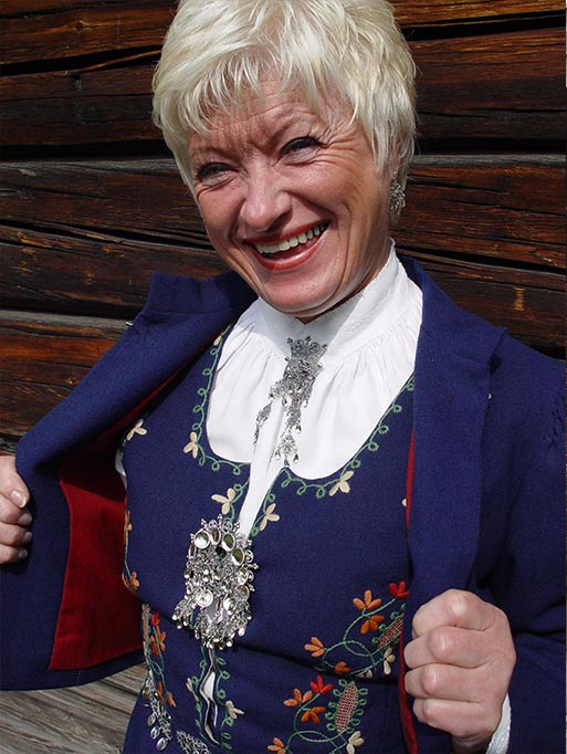 Bilde av kvinne som viser frem Solør-Odalsbunadens ytterplagg / kep